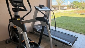 A home gym with a treadmill, elliptical, and stationary bike. - Apartments Armitage (Privlaka)