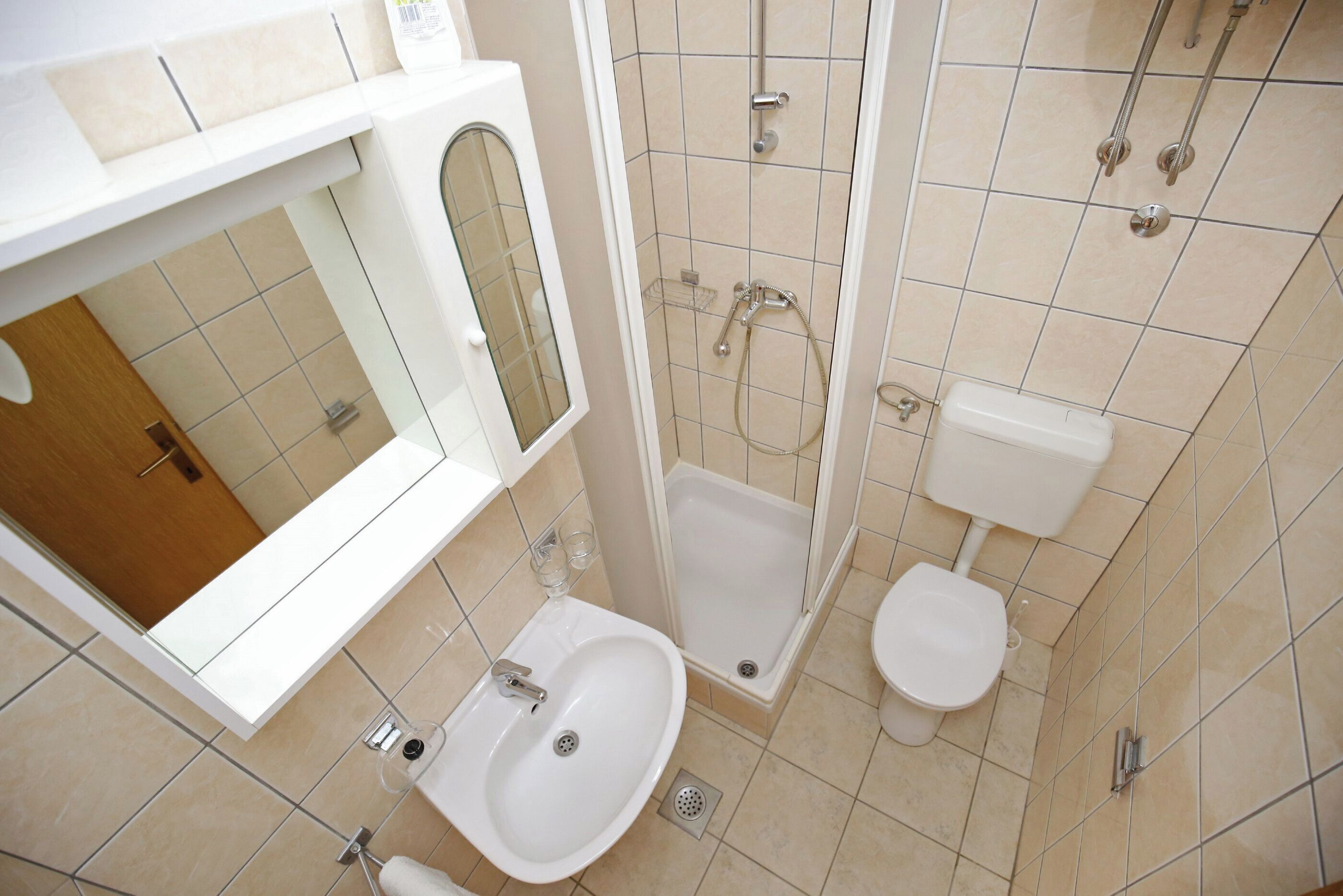 A bathroom with a sink, toilet, shower, and a mirror.