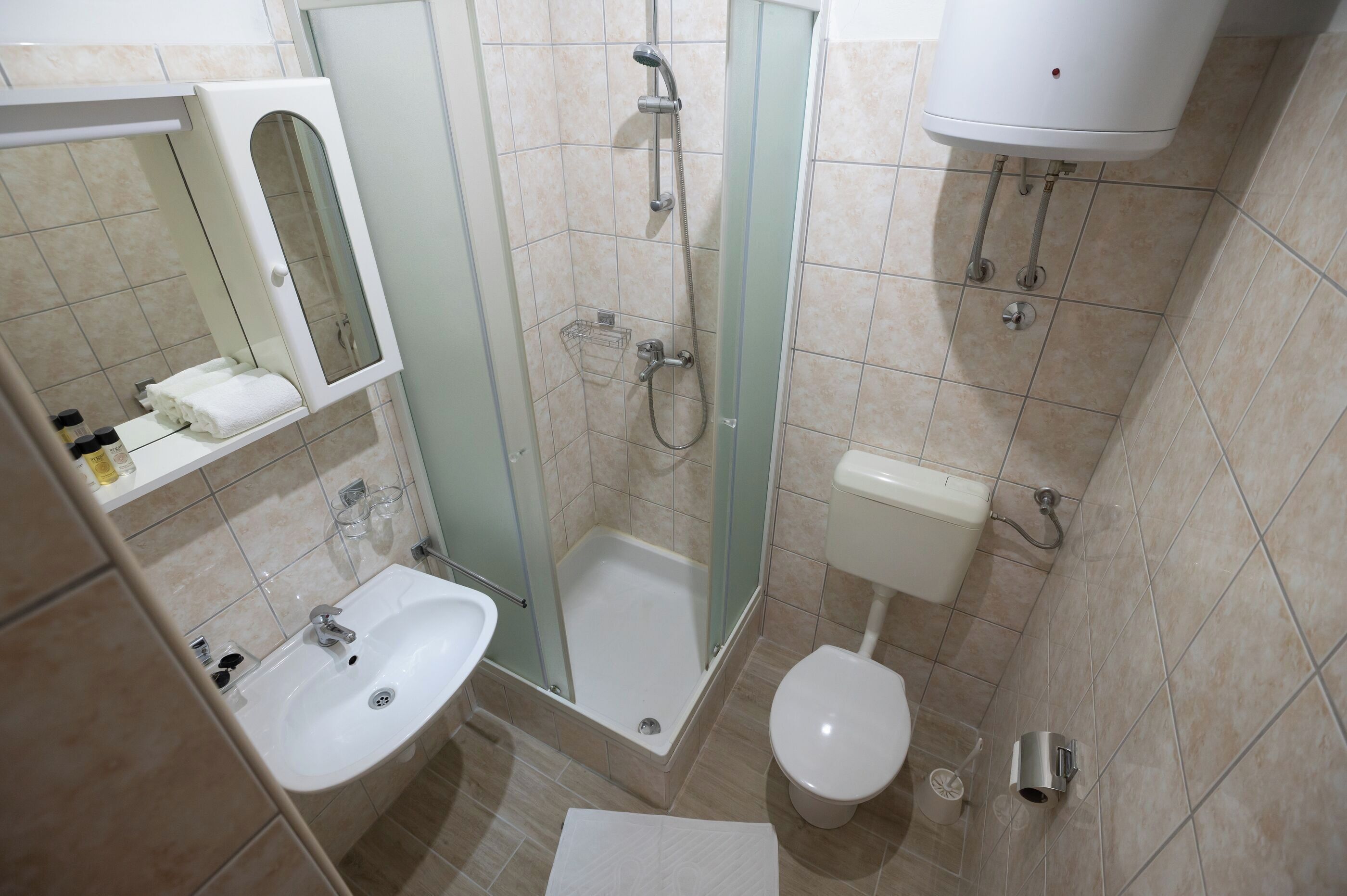 A bathroom with a shower, toilet, sink, and a glass-enclosed shower stall.