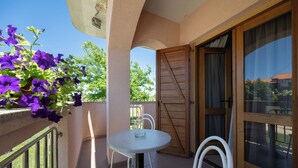 A balcony with a table and chairs, a wooden door, and a view of the outside. - Apartments Armitage (Privlaka)