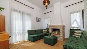 A living room with a sectional sofa, a fireplace, and a wooden cabinet. - Apartment Renata (Omisalj)