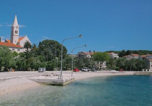A coastal town with a church, clear blue sea, and a sandy beach. - Apartments and Room Anita (Selca)