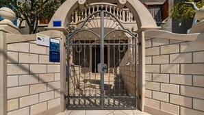 Een omheind toegangspunt met een metalen poort, bakstenen muren en een bordje dat een studioappartement aangeeft.