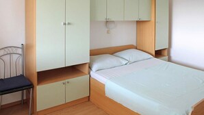 Een slaapkamer met een bed, een stoel en ingebouwde kasten.