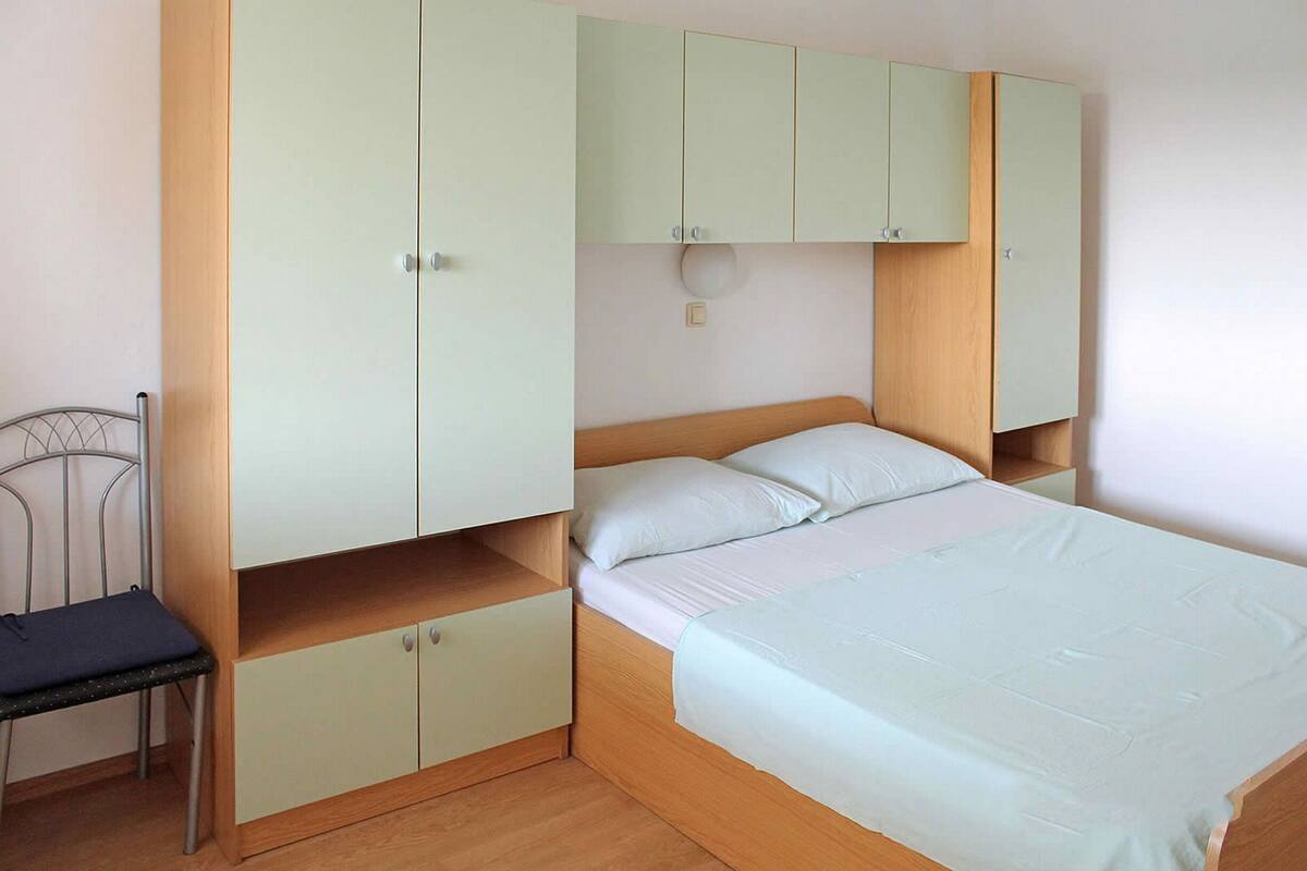 A bedroom with a bed, a chair, and built-in cabinets.