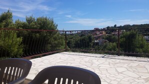 A terrace with stone flooring, metal railing, and two plastic chairs. - Apartment Roko (Vis)