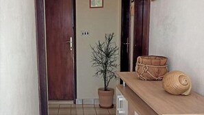 A narrow hallway with a potted plant, a wooden bench, and a small shelf with decorative items. - Apartment Roko (Vis)