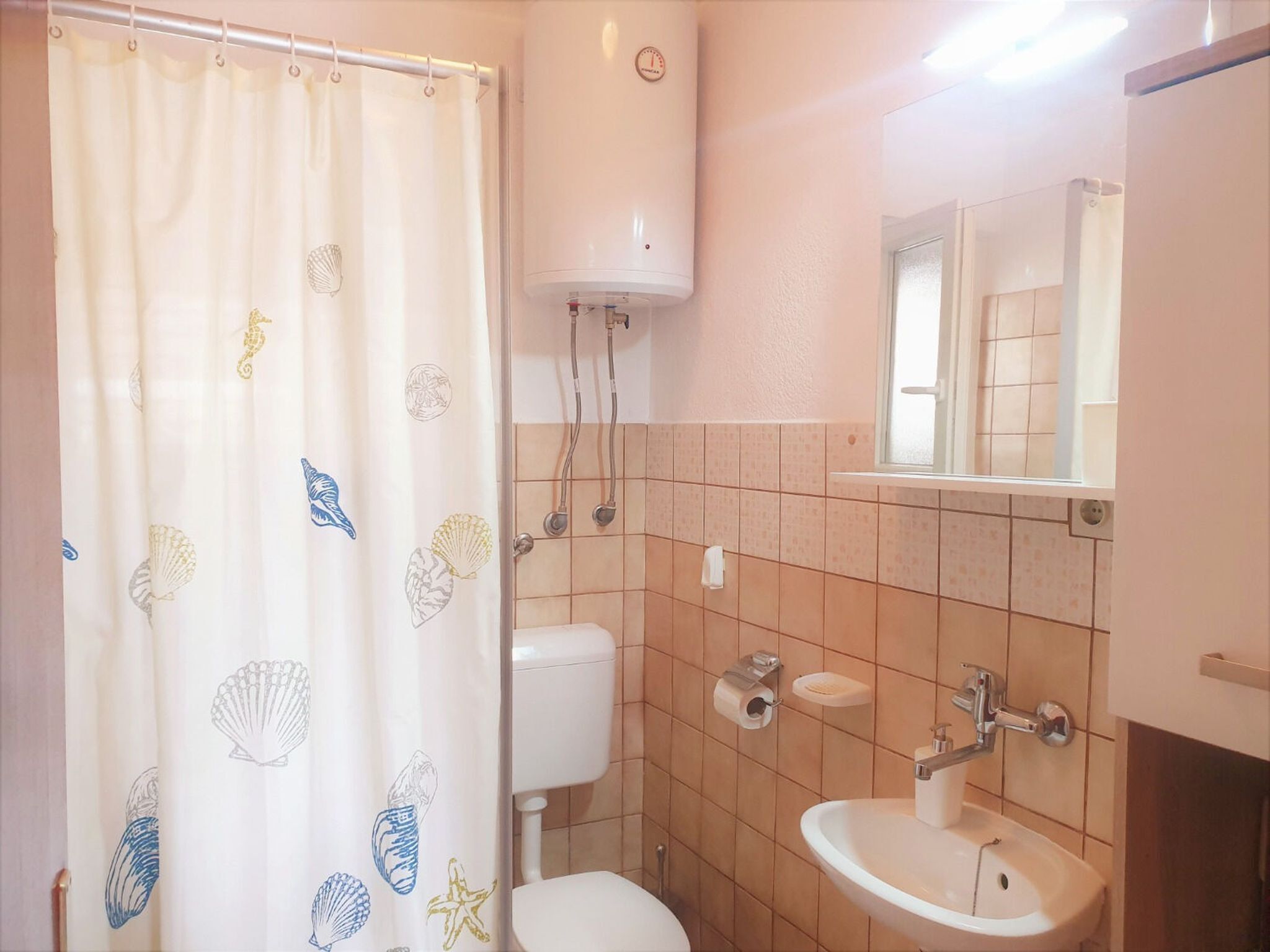 A bathroom with a toilet, sink, and shower curtain with sea creature designs.