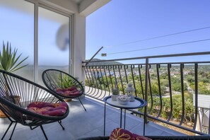 A balcony with two black wicker chairs, a small table with a white bowl and a lantern, and a potted plant. - Apartment Ivo (Marina)