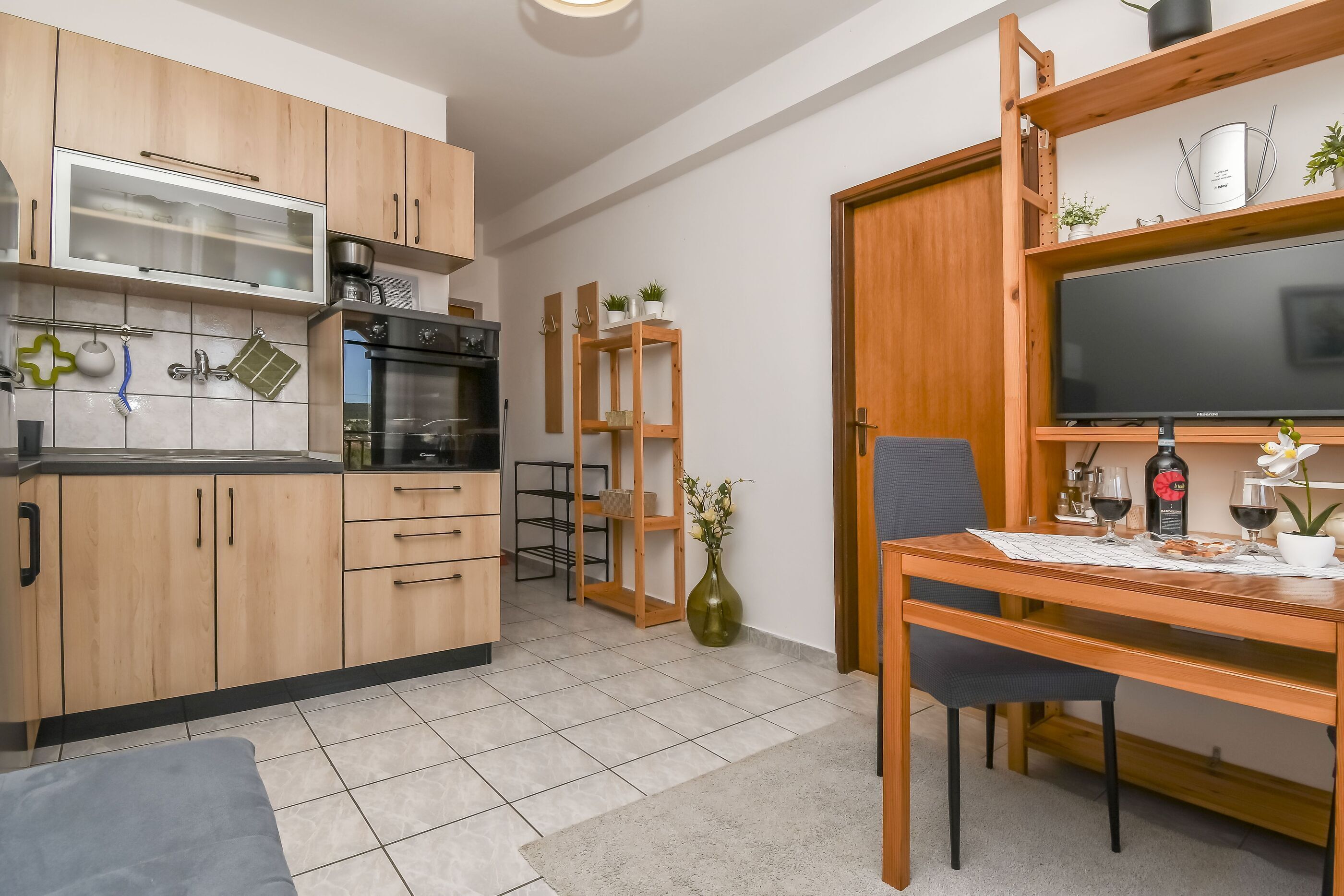 Una cocina moderna con armarios de madera, horno empotrado y comedor con mesa y sillas de madera.