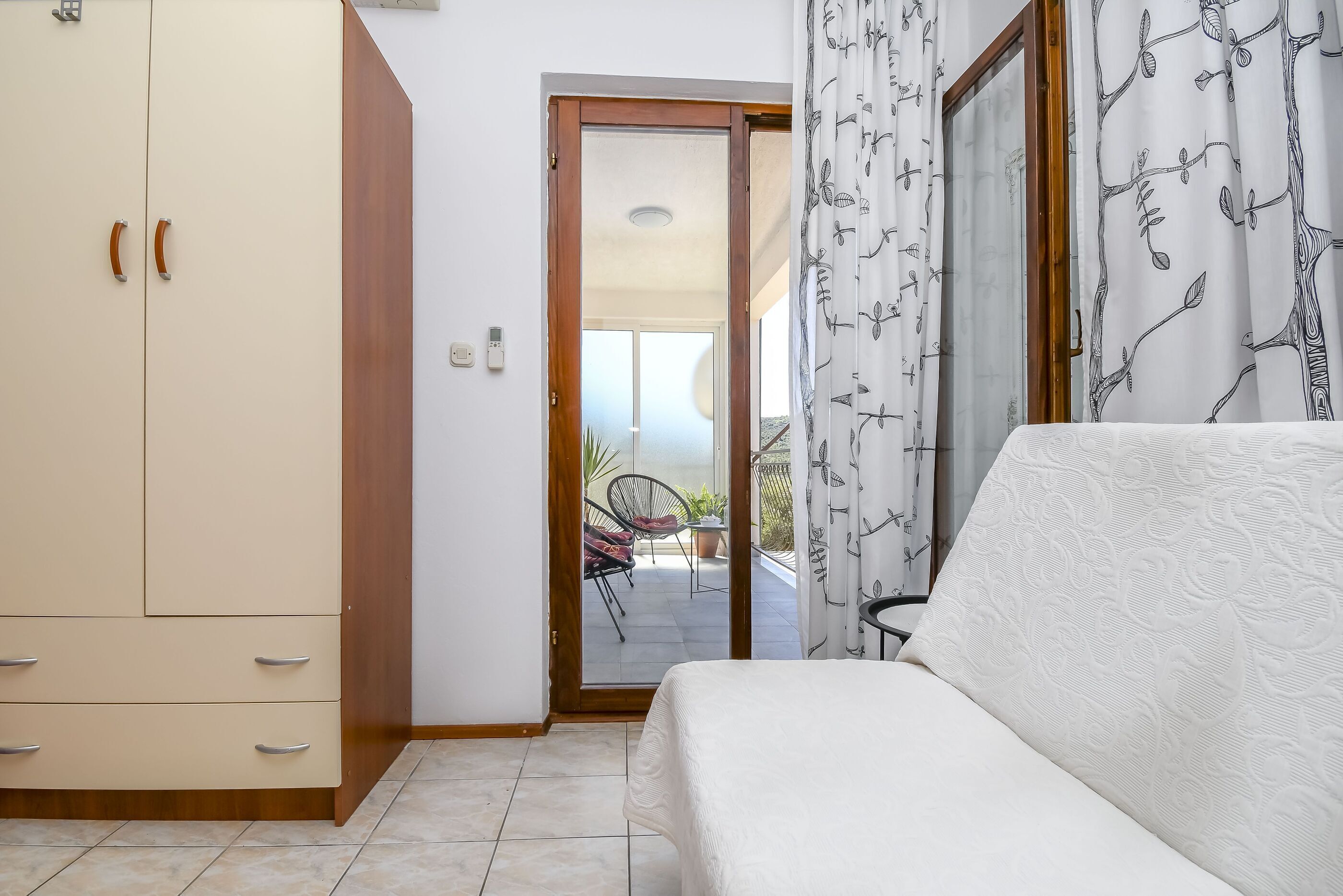 A bedroom with a bed, a wardrobe, and a sliding glass door leading to a balcony.