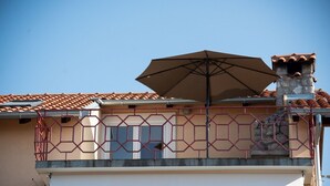 A building with a tiled roof, a large umbrella, and a garage door. - Apartment Ivona (Omisalj)