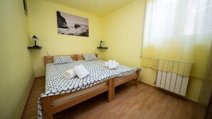 A bedroom with a bed, two bedside tables, a wall-mounted picture, and a window with curtains. - Apartment Ivona (Omisalj)