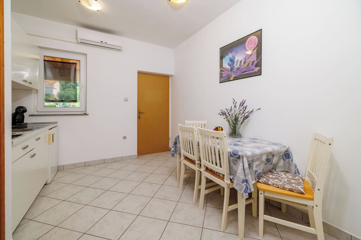 A compact kitchen with a window, a dining table with chairs, and a door.