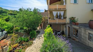 A two-story building with a garden path leading to the entrance. - Apartments Tatjana (Rab)