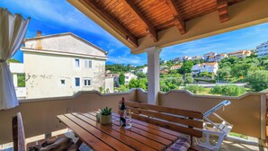 A wooden balcony with a table, a bottle of wine, and a glass. - Apartments Tatjana (Rab)