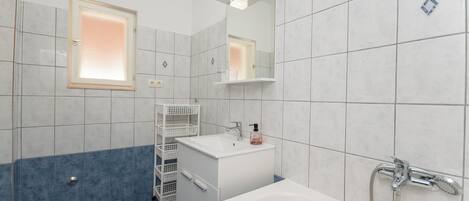 Une salle de bain moderne équipée d’une baignoire, d’un lavabo, d’un miroir et d’une douche.