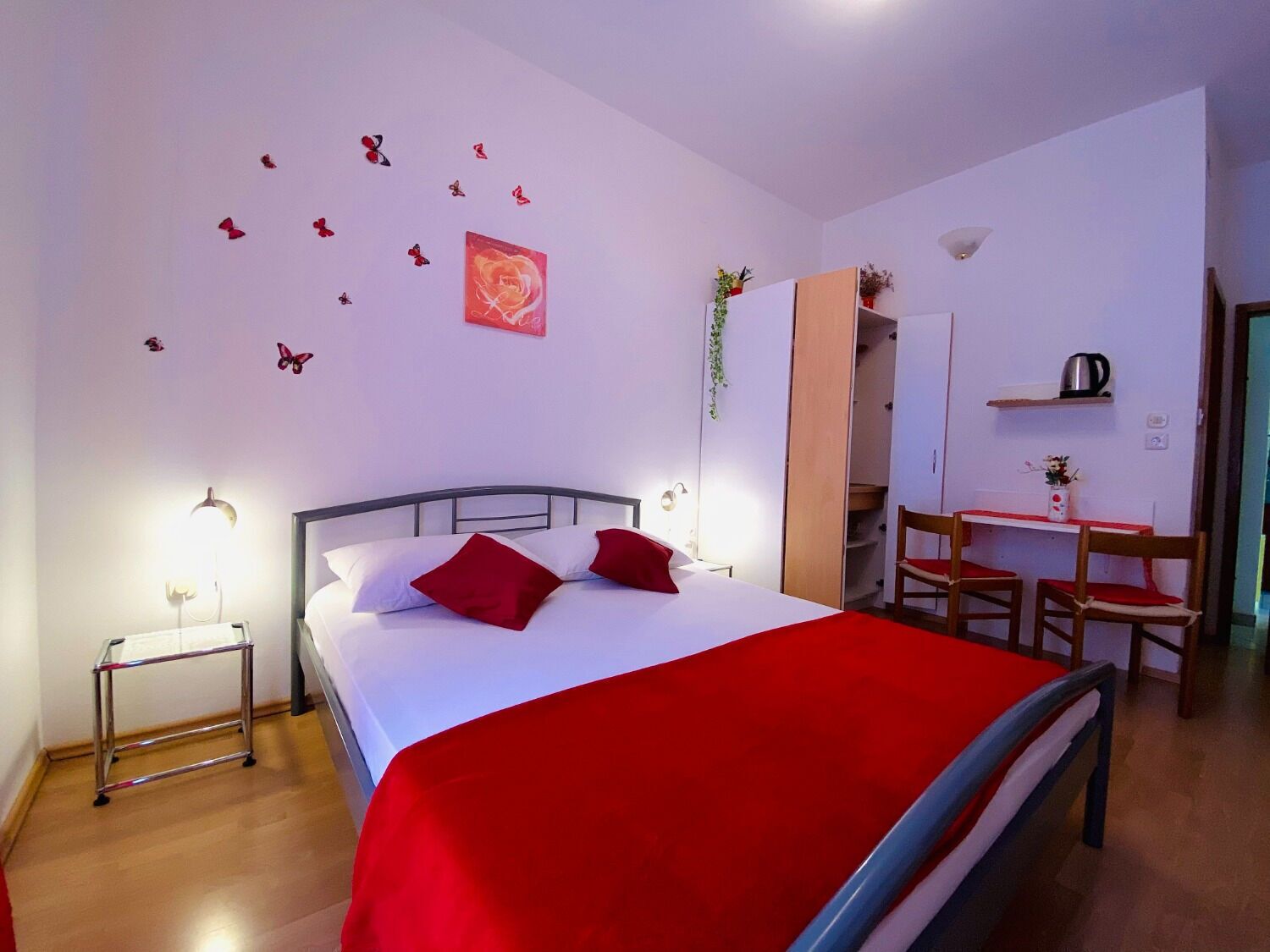 A hotel room with a bed, bedside table, and a desk with chairs.