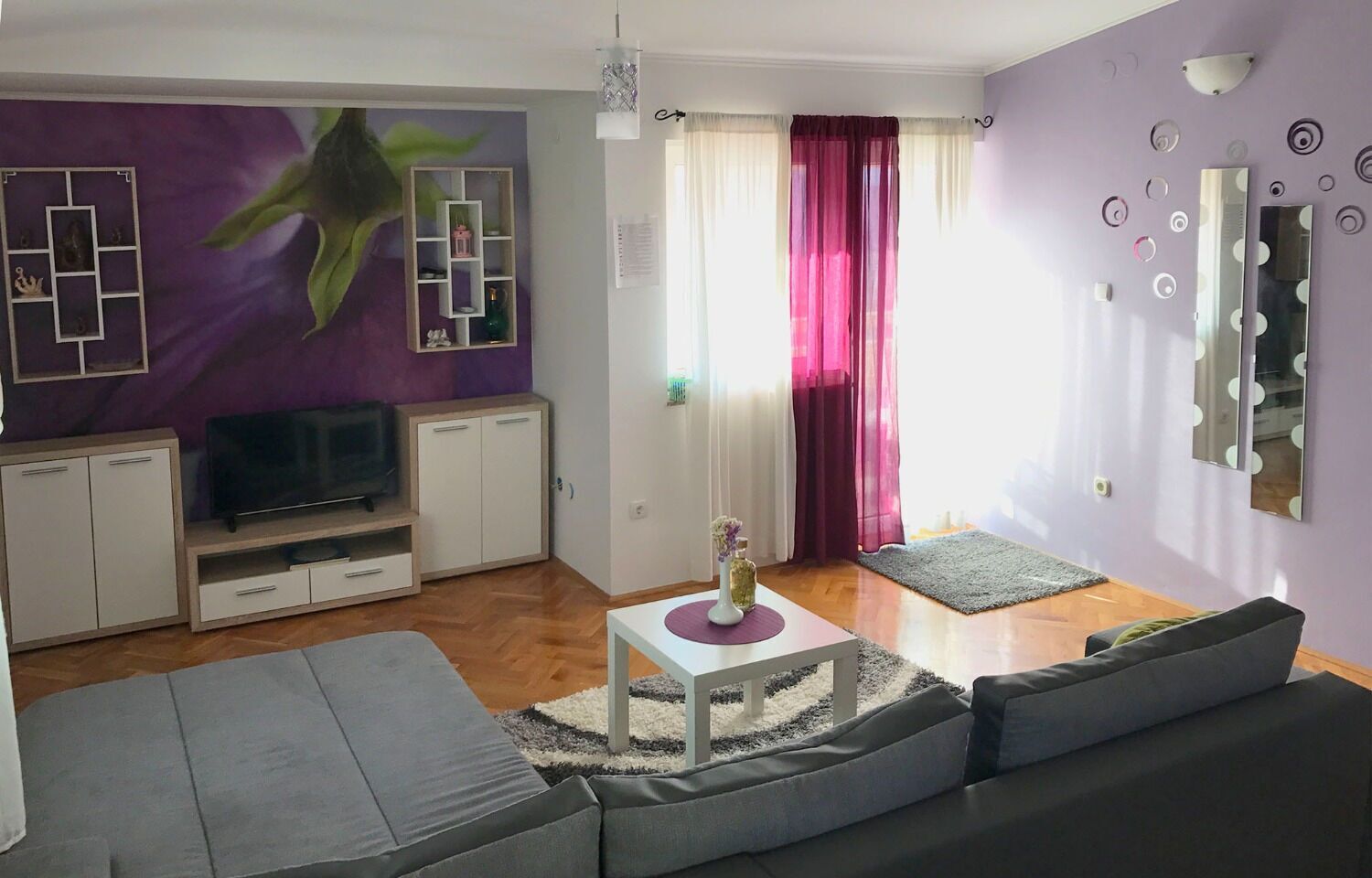 A modern living room with a sofa, TV, and decorative wall art.