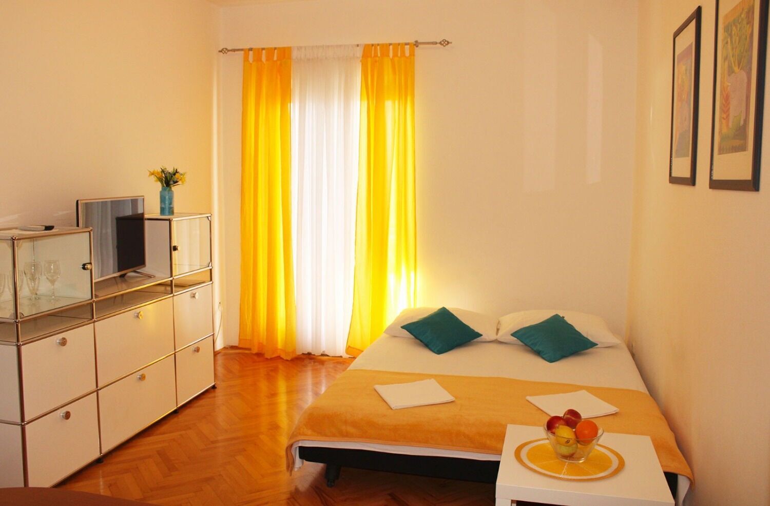 Una habitación de hotel con cama, mesita de noche y televisión sobre un mueble.