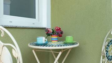 A small round table with a colorful striped mug, a green mug, and a floral arrangement.