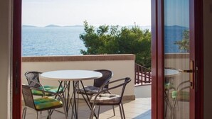 A balcony with a table and chairs, offering a view of the sea and distant mountains. - Apartments Marija (Murter-Kornati)