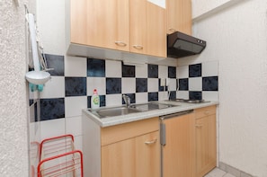 Una cucina compatta con un lavello doppio, mobili in legno e una parete rivestita a scacchi.