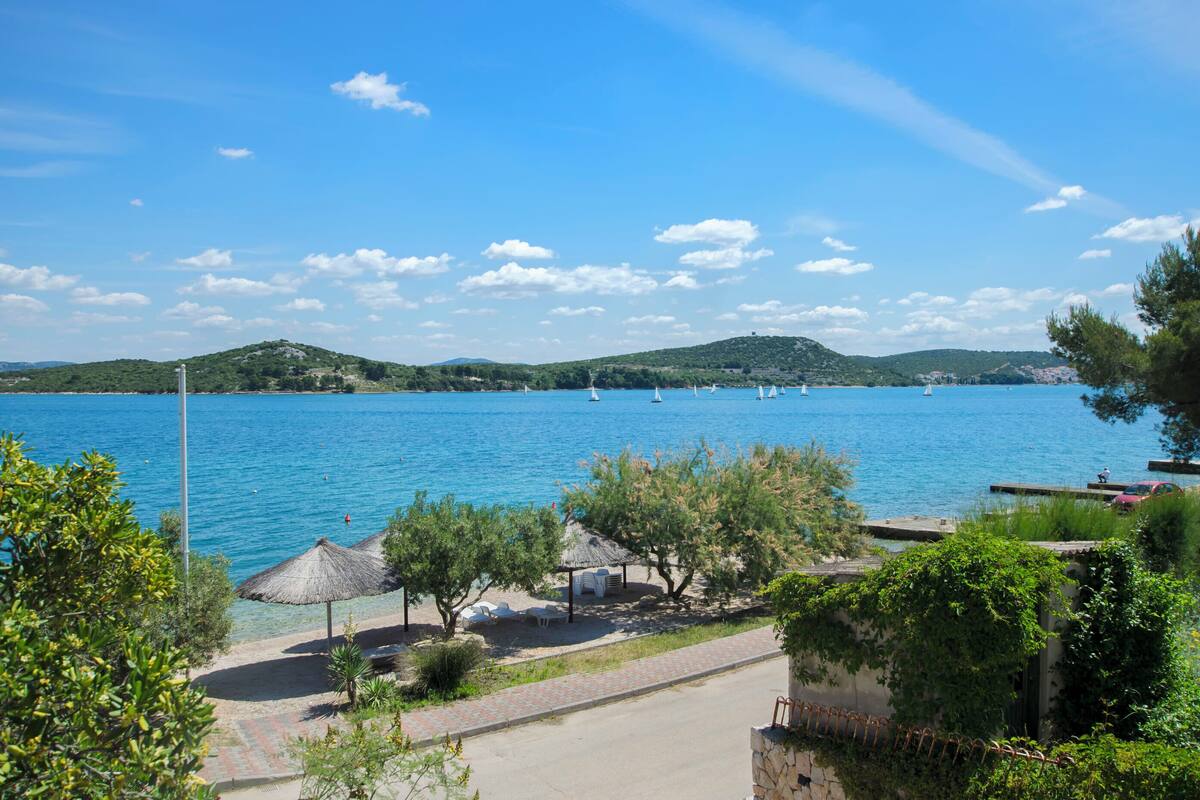 A coastal view with a clear sky, a calm sea, and a few sailboats.