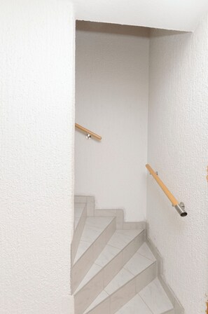 Una scala con pareti bianche e una ringhiera in legno.