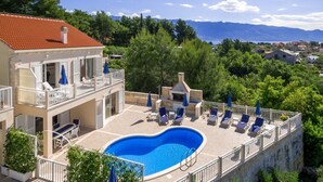 Un edificio su due piani con piscina, area relax all'aperto e vista sulle montagne.