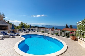 A pool area with lounge chairs and a view of the sea. - House Jure (Selca)