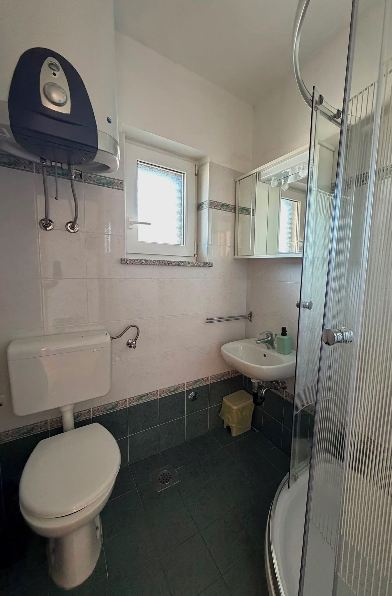 A bathroom with a toilet, sink, and shower.