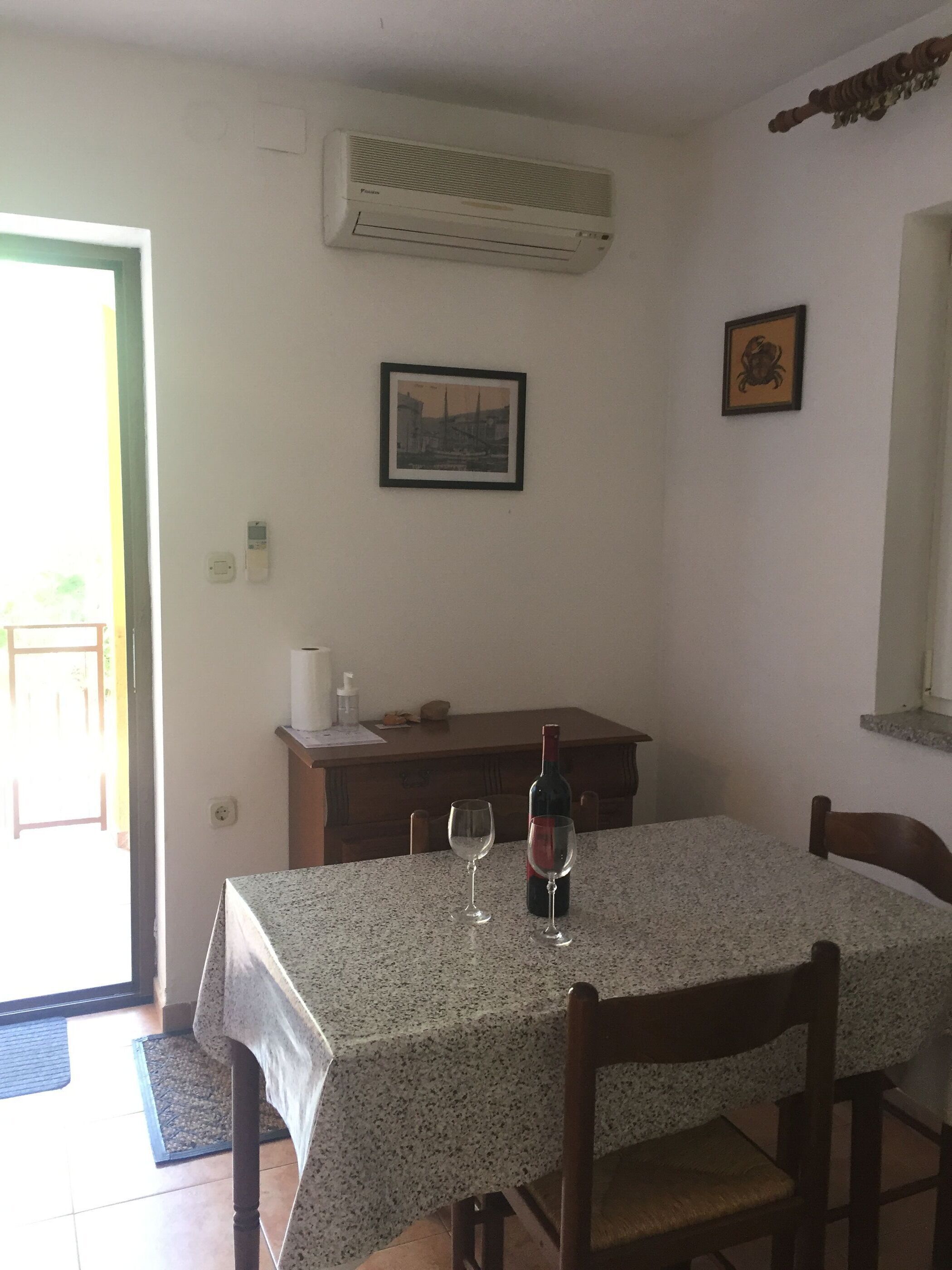 Un coin repas avec une table, des chaises, une bouteille de vin et deux verres à vin.