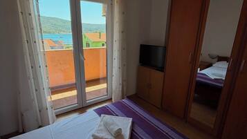 Ein Schlafzimmer mit einem Bett, einem Fernseher, einem Kleiderschrank und einer Glastür zum Außenbereich.