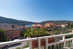 A residential area with houses, a road, and a mountain in the background. - Apartments Marija (Cres)