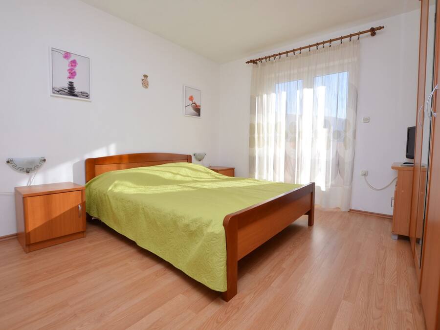 Un dormitorio con una cama de madera, una mesita de noche, un armario y una ventana con cortinas.