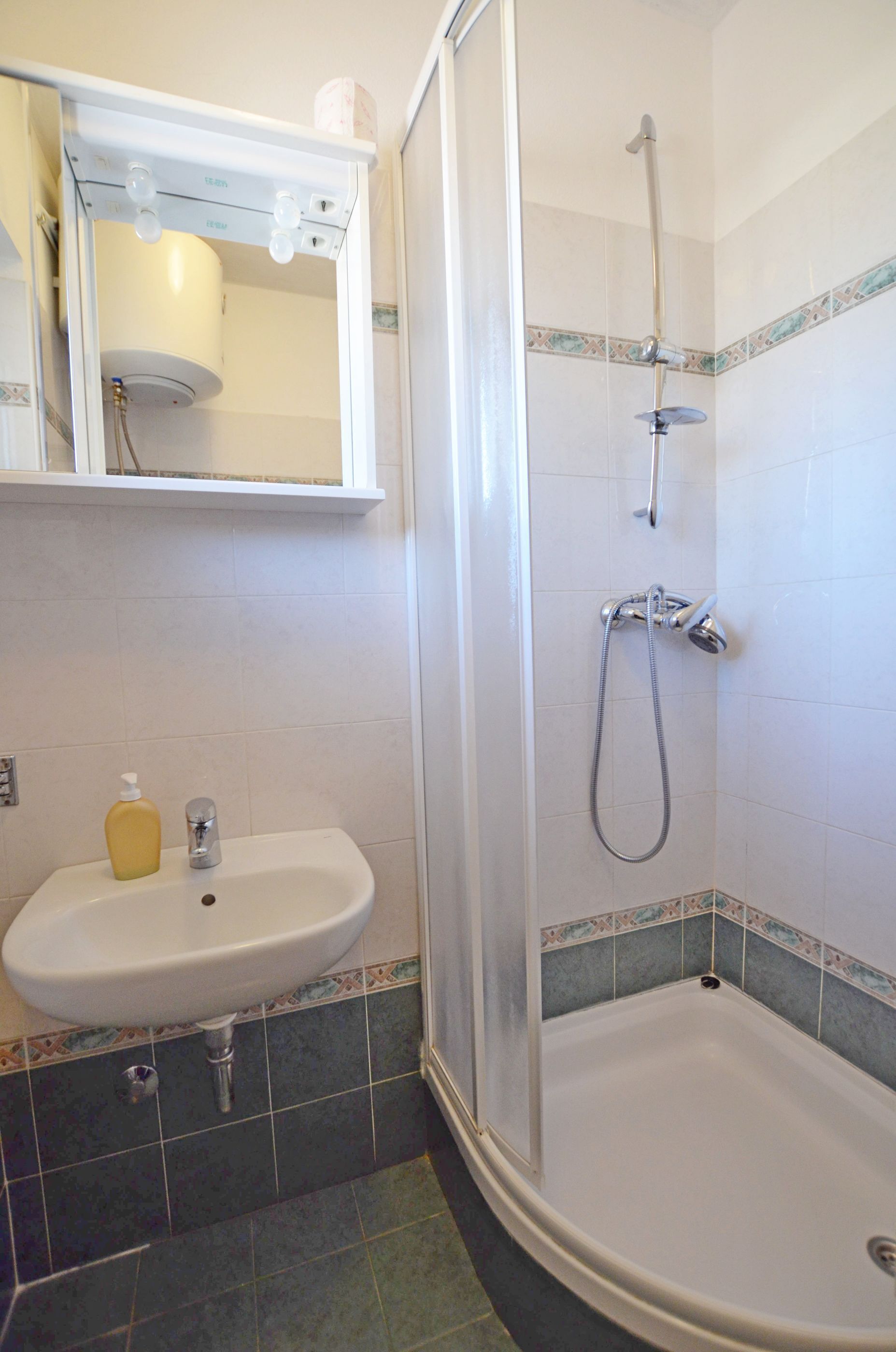 A bathroom with a shower, sink, and mirror.
