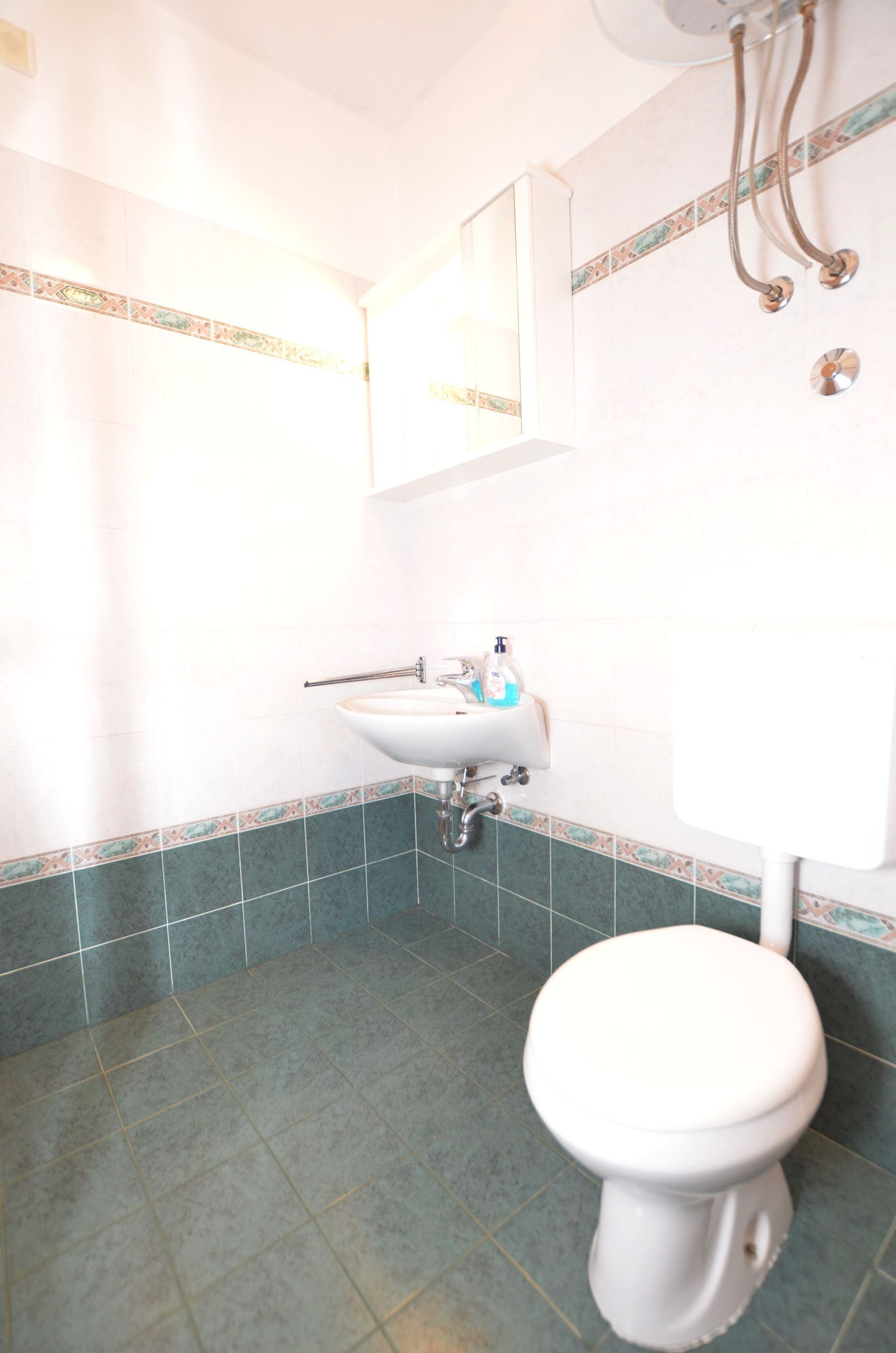 A bathroom with a white sink, a mirror, and a toilet.