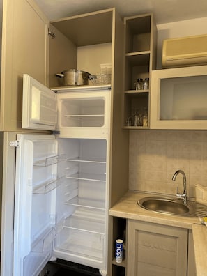 A kitchen with a built-in refrigerator, a microwave, a sink, and a cabinet with shelves.