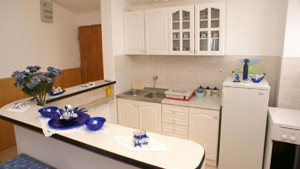 A small kitchen with white cabinets, a sink, and a refrigerator. - Apartments Mari (Blato)