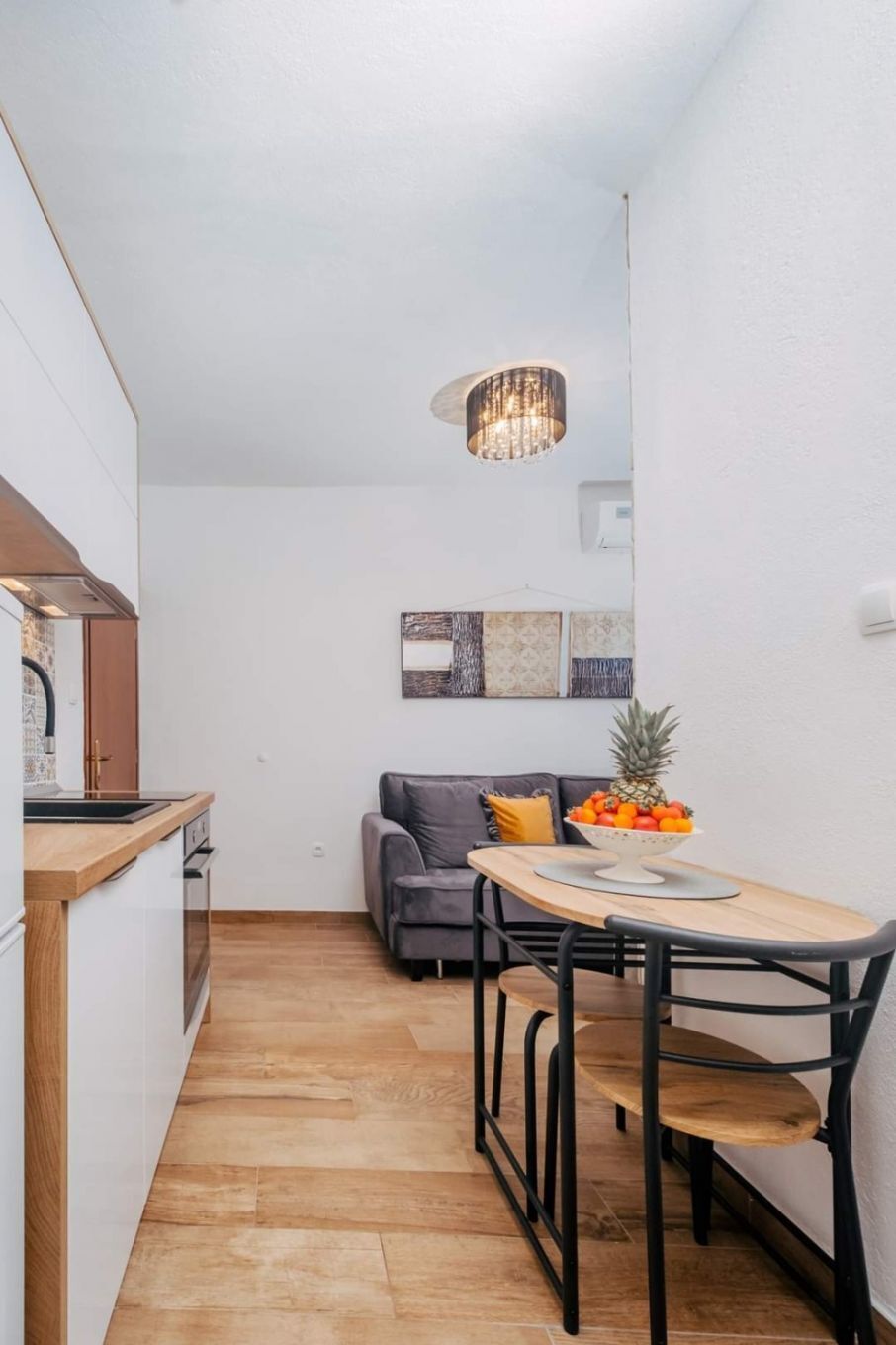 A narrow kitchen with a wooden countertop and a dining area with a table and chairs.