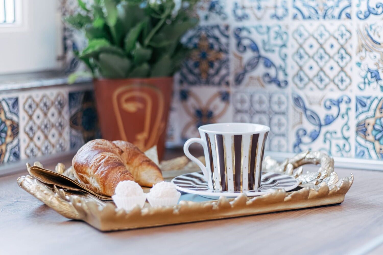 Un croissant, une tasse et une cuillère sur un plateau.