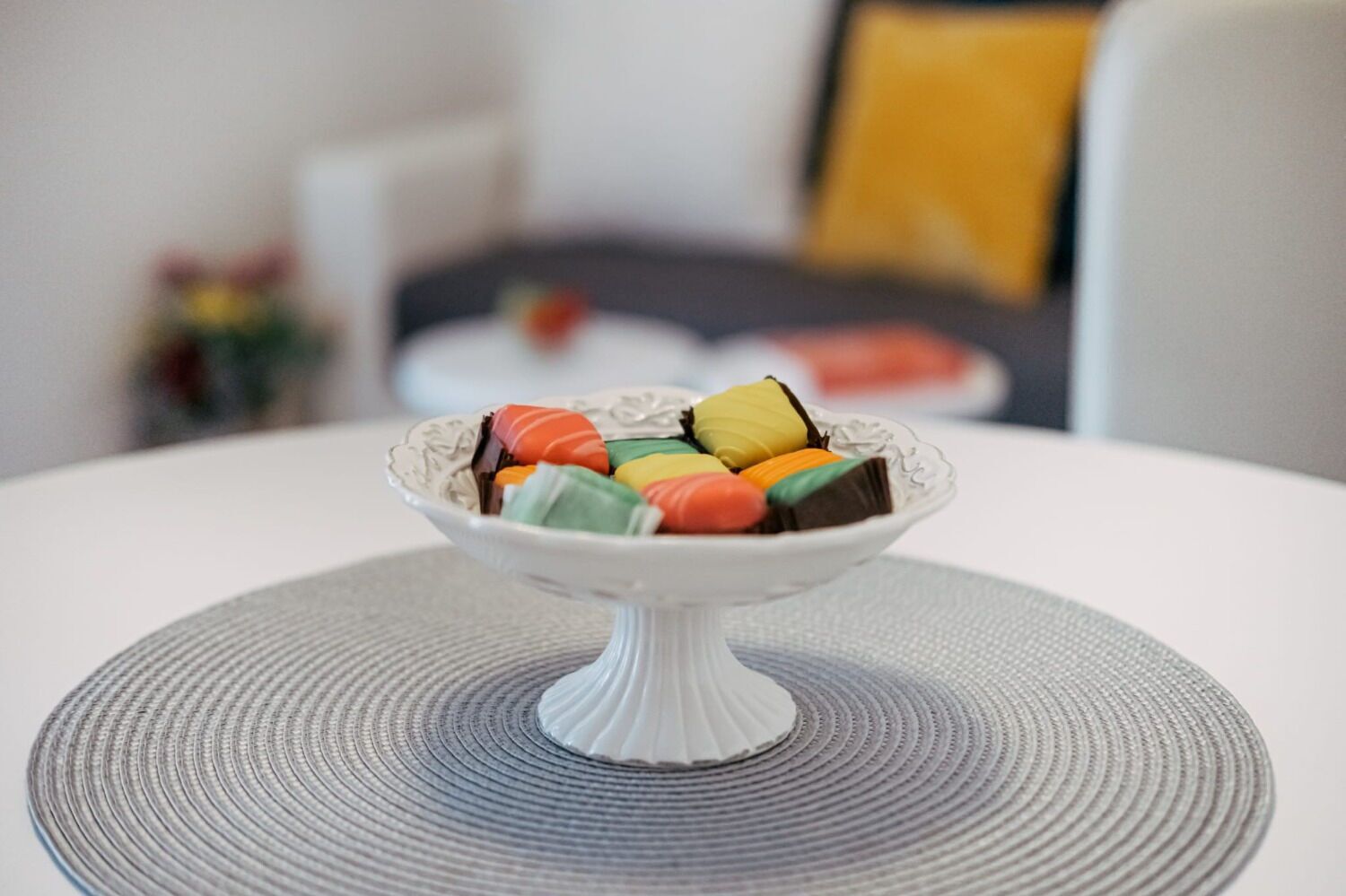 A white ceramic bowl on a round table with a textured placemat.
