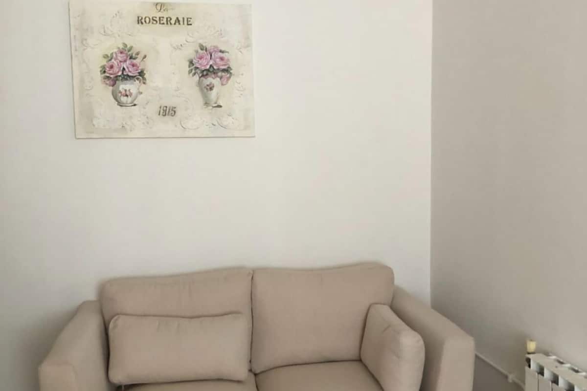 A beige sofa in a room with a white wall and a radiator.