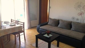 A living room with a sofa, a dining table with chairs, and a small coffee table. - Apartments Ognjen (Tisno)