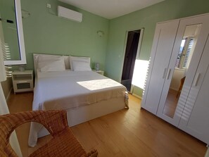 A bedroom with a bed, nightstands, a wardrobe, and a wicker chair. - House Dinko (Marina)