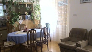 Un espace repas comprenant une table ronde, des chaises et un buffet agrémenté d’un centre de table en verre.