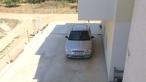 Une voiture était garée dans un parking couvert, à côté d’un immeuble.