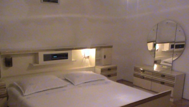 Une chambre moderne avec un grand lit, des tables de chevet, un miroir et un panneau de commande fixé au mur.
