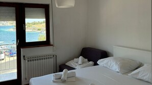 Ein Hotelzimmer mit Bett, Meerblick und Jalousien.